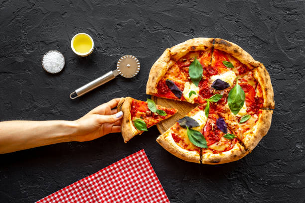 istock Female hands hold slice of pizza. Overhead view 1350628297