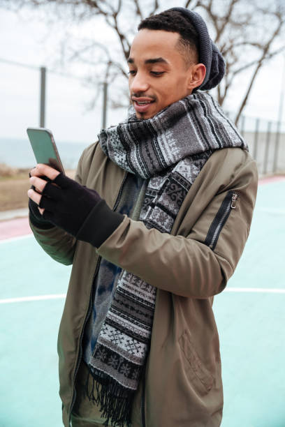 istock Concentrated african man using smartphone outdoors in autumn 1350628759