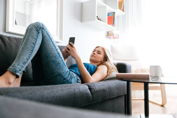 istock Woman lying on sofa and using cell phone at home 1350630543