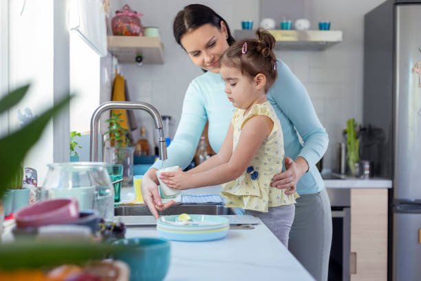 istock Mother and daughter washing dishes 1350630549