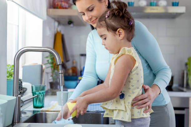 istock Mother and daughter washing dishes 1350630563