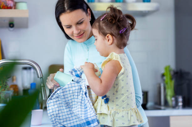 istock Mother and daughter washing dishes 1350630570