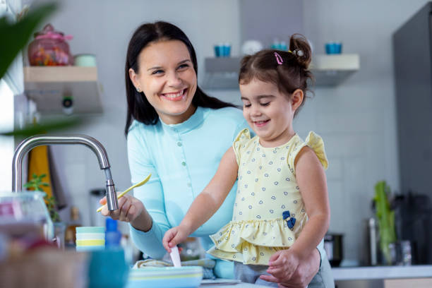 istock Mother and daughter washing dishes 1350630585