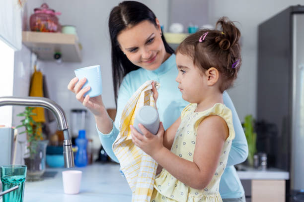 istock Mother and daughter washing dishes 1350630601