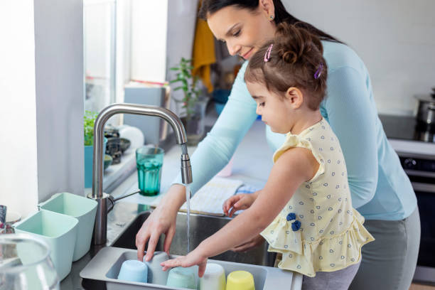 istock Mother and daughter washing dishes 1350630622