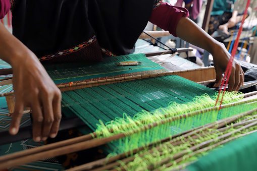 Close up of hands doing weaving work using traditional tools
