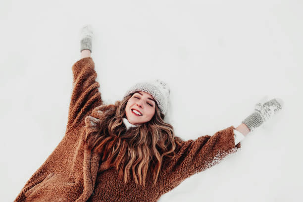 młoda piękna kobieta kładąca się na białym śniegu w zimowym lesie - snow ski zdjęcia i obrazy z banku zdjęć