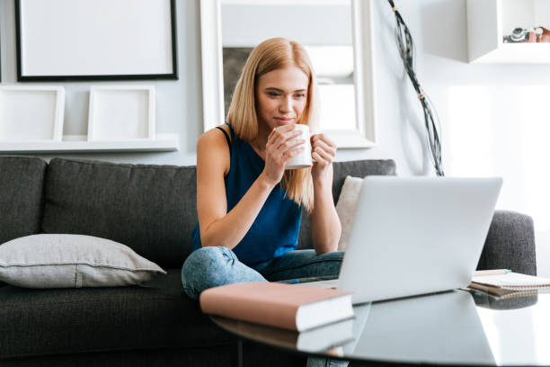 istock Thoughtful woman drinking coffee and using laptop at home 1350632896
