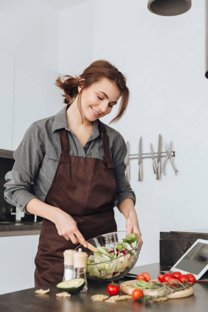 istock Pretty woman cooking in kitchen using tablet 1350633701