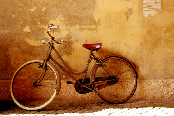 Vintage Bicycle Against Grunge Wall Sepia Toned Antique european-style bike leaning against a city wall. iso lock stock pictures, royalty-free photos & images