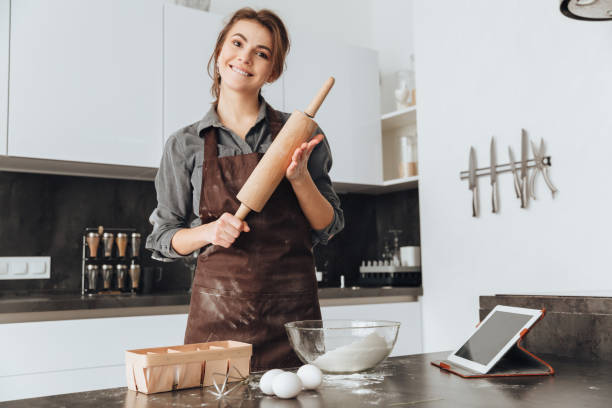 istock Young pretty woman standing in kitchen and cooking 1350634007