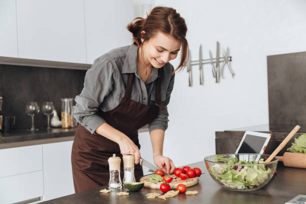 istock Pretty woman cooking in kitchen using tablet 1350634023