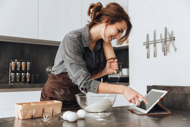 istock Young pretty lady standing in kitchen and cooking 1350635460