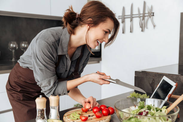 istock Pretty woman looking at tablet and cooking 1350636302