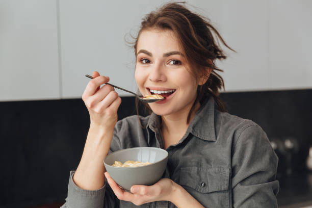 istock Cheerful woman standing in kitchen while eating 1350636559