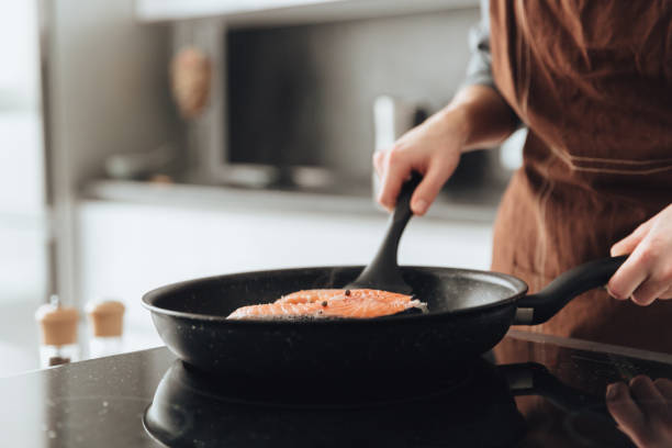 istock Cropped image of young lady cooking fish. 1350637316