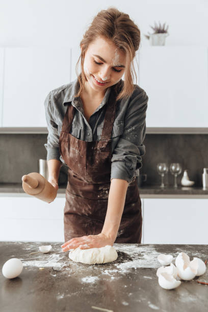 istock Pretty lady standing in kitchen while cooking the dough. 1350637426