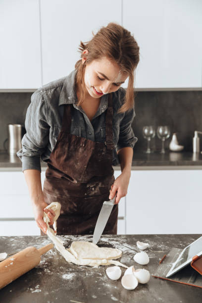 istock Happy woman standing in kitchen while cooking 1350637442