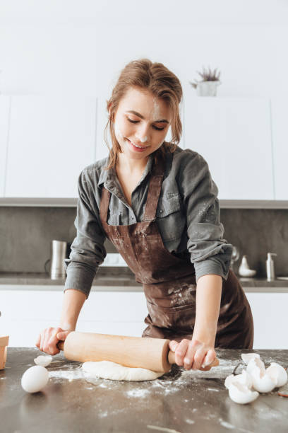 istock Happy lady standing in kitchen while cooking the dough 1350637684