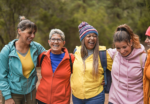 Happy multiracial women having fun embracing each other on trekking day outdoor - Healthy lifestyle and multi generational friendship concept