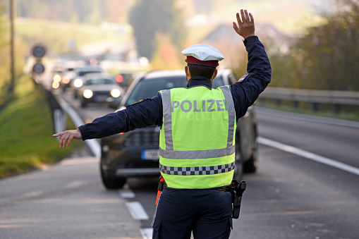 A police officer from behind stops cars for exit controls from the corona high incidence risk area Gmunden by the armed forces and police, Austria, Europe