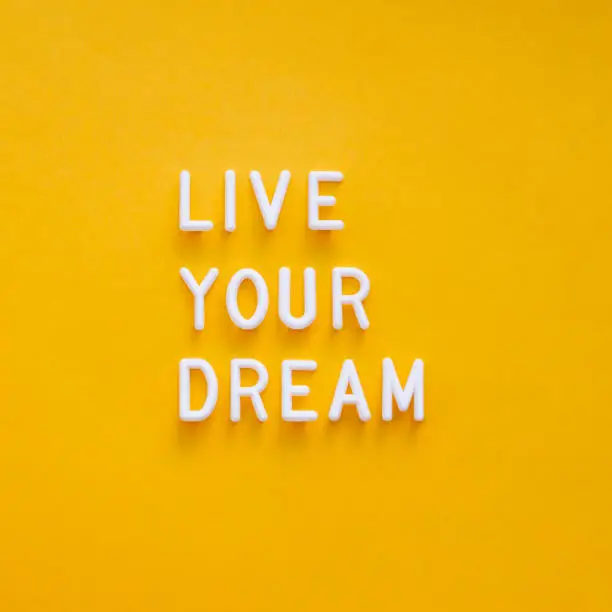 Live your dream. Motivating and inspiring phrase on bright yellow background. Top view on lifting spirit message. Creative rise.