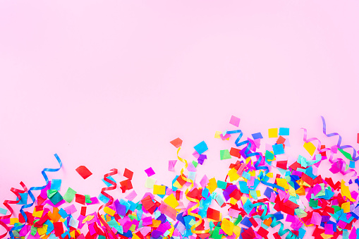 Celebration, party or birthday backgrounds: multi colored confetti arranged at the top border of a pink background making a frame and leaving useful copy space for text and/or logo. High resolution 42Mp studio digital capture taken with SONY A7rII and Zeiss Batis 40mm F2.0 CF lens