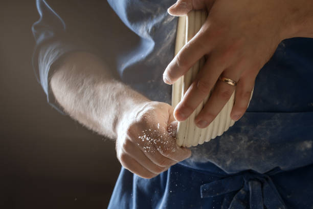 istock Male baker lightly flouring proofing basket for home made sourdough bread. 1350649191