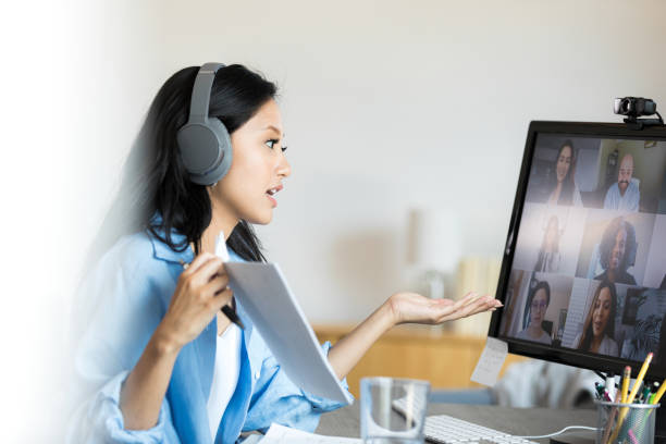 istock Female teacher uses desktop PC to teach virtual college course 1350649362