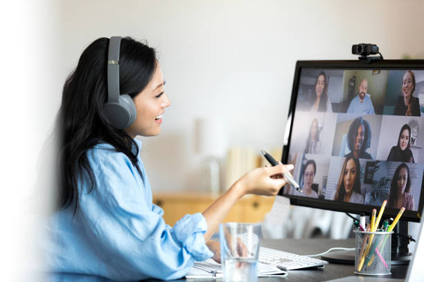 istock Mid adult teacher smiles and gestures while teaching online class 1350649366