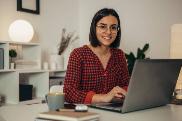istock Beautiful woman using a laptop while working from home 1350649455