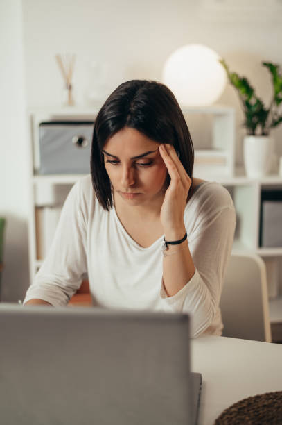 istock Woman feeling tired and stressed while using a laptop and working from home 1350649459