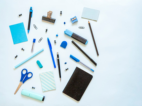 Flat lay of blue and black stationery for journaling, crafting and writing. Come back to school supplies for creative students. Top view of scissors, pencils, marker, notebook and blank sticky notes.