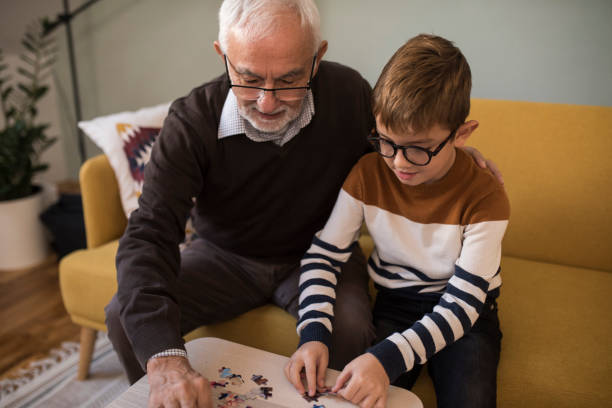 istock Senior man helping his grandson to make a jigsaw puzzle 1350651085