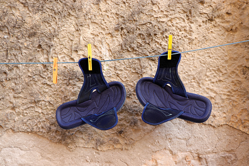 Pair of men's beach sandals drying on a clothesline.