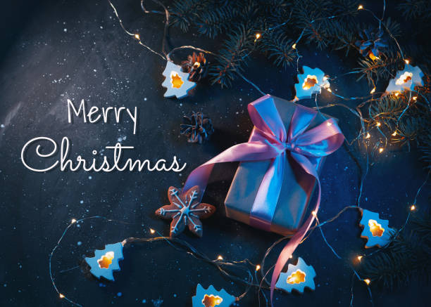 istock Merry Christmas greeting card top view, gift box on the table with Christmas tree branches, cones and garland 1350654095