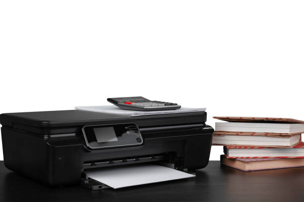 istock Printer and stack of books on black table against white background 1350655023