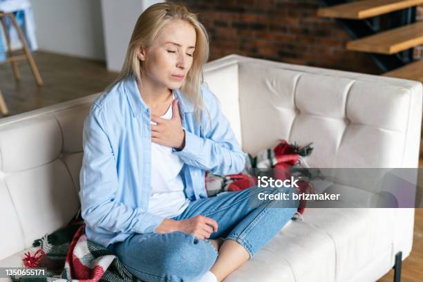 Woman Feeling Chest Pain Sitting At Home Stock Photo - Download Image Now - Heart - Internal Organ, Stroke - Illness, Pain