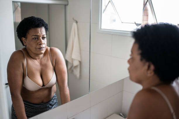 Mature woman looking in the mirror at home Mature woman looking in the mirror at home vanity mirror stock pictures, royalty-free photos & images
