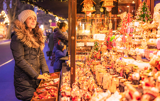 A woman browing outdoor Christmas market stalls for gifts.
