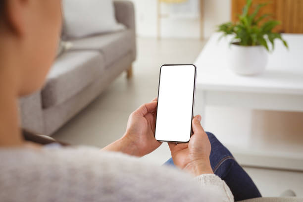 istock Asian woman sitting on sofa, using smartphone with copy space on screen 1350658715