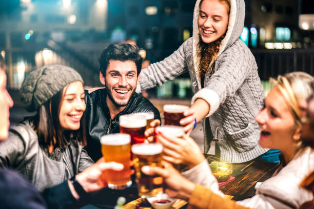 happy people drinking beer at brewery bar out doors - multicultural life style concept with genuine friends enjoying time together at open air restaurant patio - vivid filter with focus on guy - restaurant dinner dining people imagens e fotografias de stock