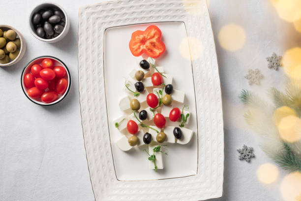 istock Christmas tree of cheese, tomatoes and olives on white tablecloth 1350663290
