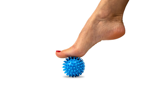 Relaxation of the muscles of the foot with a spiky silicone massage ball, physiotherapy at home. Relieve foot fatigue after wearing high-heeled shoes.