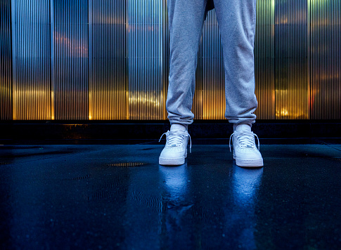 Man with white sneakers standing outdoors in city, Low angle view