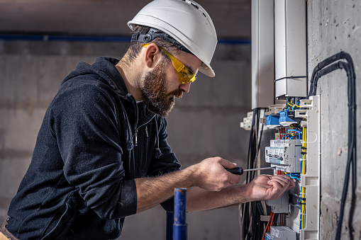 Un electricista masculino trabaja en una centralita con un cable de conexión eléctrica. photo