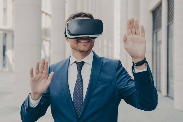 istock Businessman in suit trying out and experiencing virtual reality using mobile VR headset outdoors 1350674629