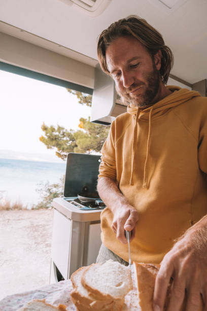 istock Man prepares breakfast in his van, cuts slices of bread 1350675428