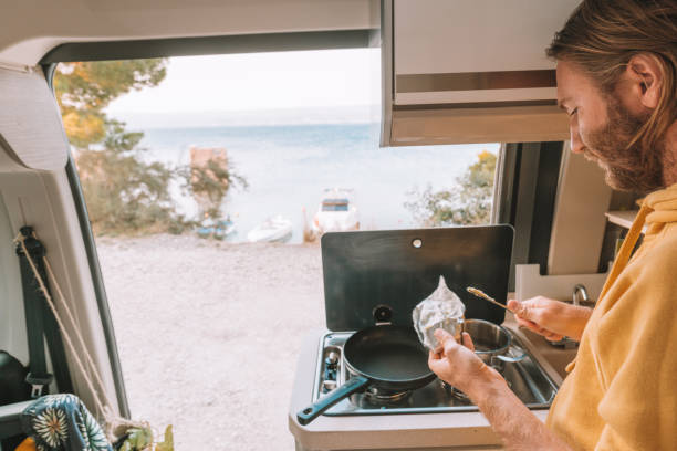 istock Man prepares breakfast in his van, sea view 1350675447