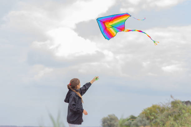 istock a girl flies a bright different-colored kite into the sky 1350675662